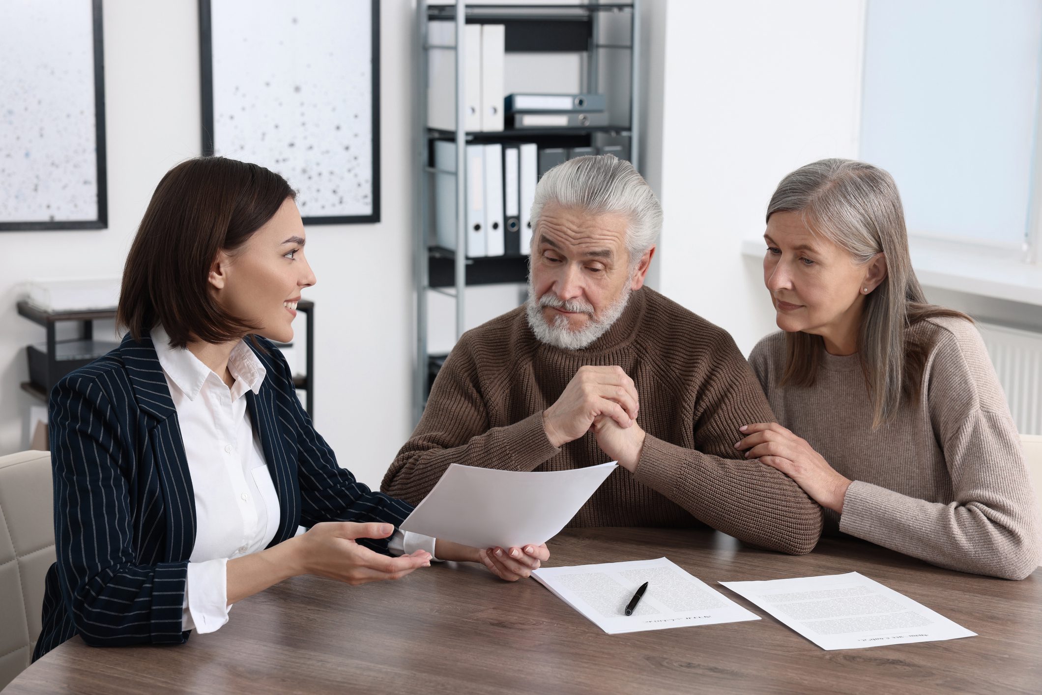 Woman advising senior couple with documents.